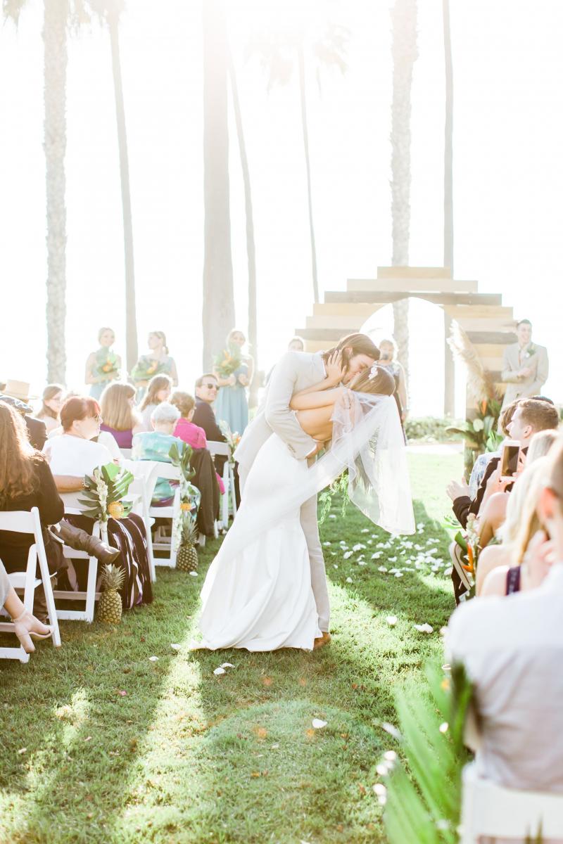 A couple poses and tilts over for a personal moment on the wedding aisle on the Ole Hanson Beach Club Grand Lawn